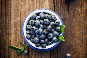 Fresh blueberries in a ceramic bowl on a wooden table top view