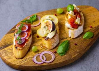 Bruschetta sandwiches on gray background. Assorted snacks on wooden board.