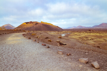 Barren volcanic landscape with a lonely path towards El Cuervo (