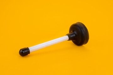 A plunger with a white handle on a yellow background
