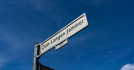 "Zum Langen Jammer" (german: "To the long misery") unusual street name street sign against a blue sky in the Friedrichshain district of Berlin, Germany. 