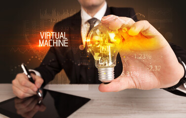 Businessman holding lightbulb with VIRTUAL MACHINE inscription, Business technology concept