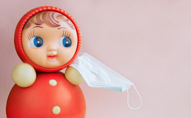 Matryoshka in a mask on a pink background. Concept of protecting children from coronavirus. Close-up. Place for text.