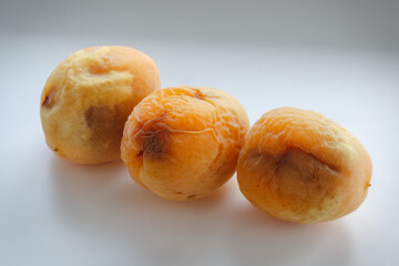 A group of old and spoiled apricots on a white background. Non-isolated photography