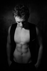 Fototapeta premium Handsome male with open waistcoat revealing defined pecs and muscular sixpack abs looking down