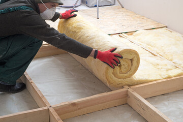 worker insulates the floor with mineral wool