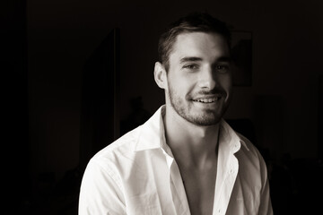 Fototapeta premium Portrait of handsome smiling young man with open shirt looking at camera