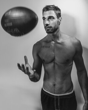 Black And White Portrait Of Young Attractive Topless Muscular Man With Beard Tossing American Football