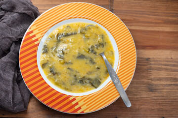 vegetable soup with spinach on plate on wooden background
