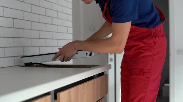 Worker installing assembling induction kitchen stove top, real time