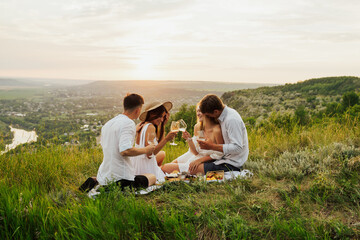 Cheerful friends enjoying a leisurely picnic on the mountain with beautiful landscape. They having a picnic and having fun. Copy space.
