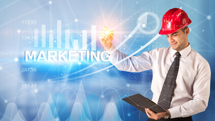 Young businessman with helmet drawing MARKETING inscription, modern business technology concept