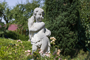 Fototapeta na wymiar Engel Statue Stein Sommer Garten Rose Natur