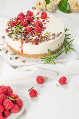 Cheesecake with raspberries, chocolate, hazelnuts and rosemary leaves on kitchen coutertop