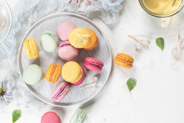 Colorful french macaroon cakes. Macaroons with jasmine flowers and tea on white table background. Selective focus