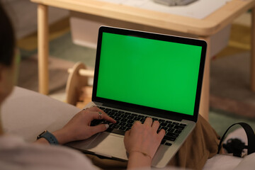 over shoulder view of people using green screen laptop computer at home. working at home concept. blur background