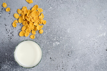 Corn flakes on a concrete background and milk in a glass. Flat top view. Copy space