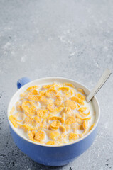 Corn flakes in milk. Blue Cup. Healthy and nutritious Breakfast for a child. Copy space.