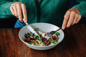 Croped image of woman eating exquisite salad dish in a bowl. No head.