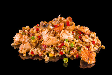 Delicious risotto with chicken, peas, mushrooms, corn and soy sauce with reflection, isolated on black background