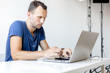 a young man works at a laptop in a bright room