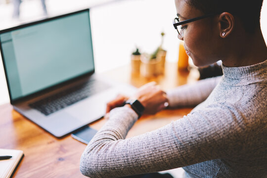 Back view of afro american female designer checking time on modern watch hurrying to complete project in time working on freelance, businesswoman waiting for confirmation of payment in feedback