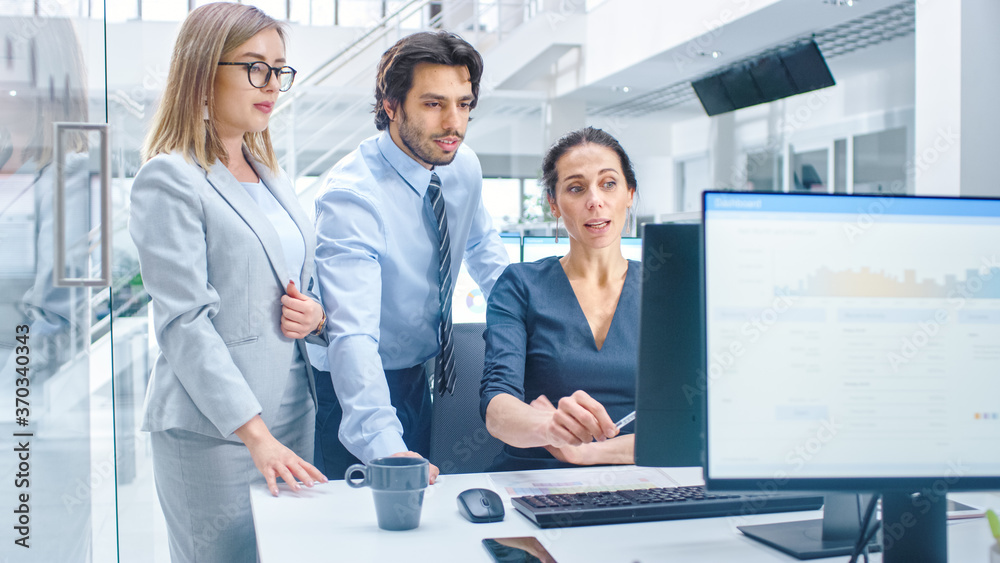 Poster In Bright Modern Office: Office Worker Sitting and Working at Her Desktop Computer, Discusses Problem Solution with Her Project Manager and Team Leader. Young Businessmen Planning and Problem Solving