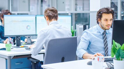 In the Big Busy Corporate Office Businessman Works on Desktop Computer, Around Him Businesspeople and Experts Working with Clients, Having Discussions and Analysing Statistics