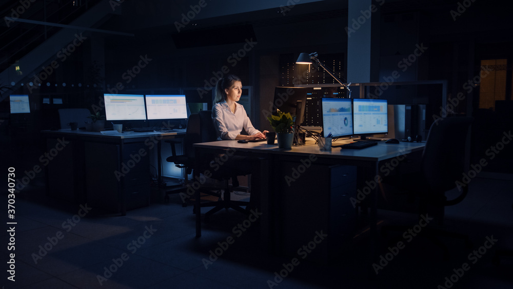 Poster working late at night in the office: businesswoman uses desktop computer, analyzing, using documents