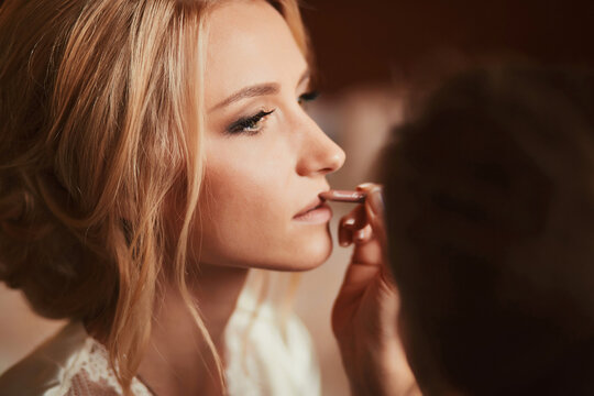 Make-up artist doing make up for young beautiful bride applying wedding make-up