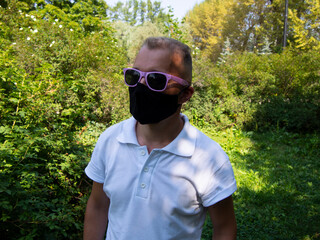 A young man in a black mask on his face in a Park