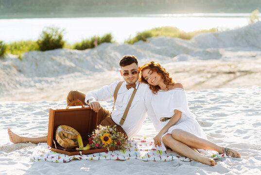Picnic on the sand near the lake in summer. Beautiful young couple