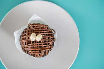 Homemade chocolate cupcake on a white dish on a turquoise background.Copy space. Homemade food...