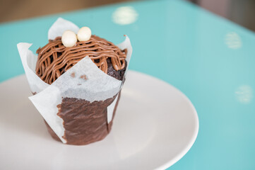 Delicious chocolate cupcake on a white dish on a colorful background.Copy space. Small business concept