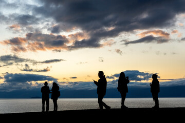 Fototapeta na wymiar Faceless group of people on top of a mountain watching sunset, silhouette of group of people taking pictures outside during sunrise or sunset