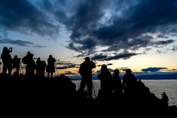 Fototapeta na wymiar Faceless group of people on top of a mountain watching sunset, silhouette of group of people taking pictures outside during sunrise or sunset