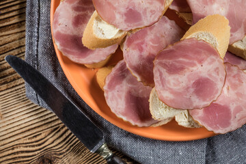 Sandwich made of wheat bread, butter and slices of dry-cured sausage.