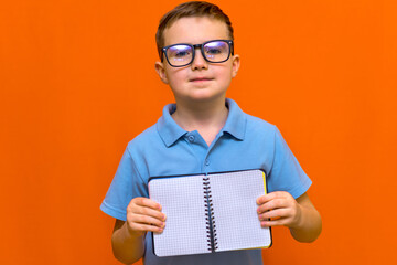 Caucasian schoolboy holding a banner isolated on orange background