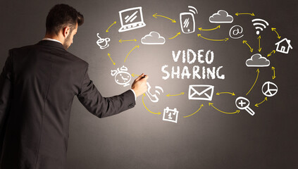 businessman drawing social media icons with VIDEO SHARING inscription, new media concept