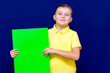 Happy calm caucasian child boy holding a poster for your information on the blue background