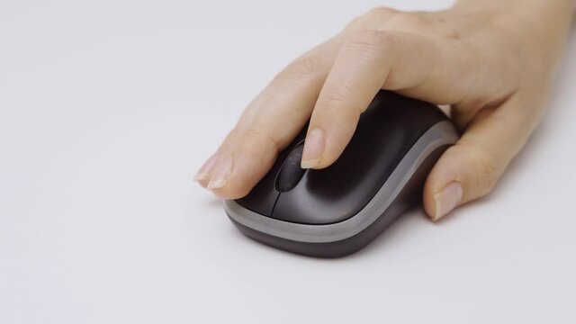 Hands move wireless computer mouse close to camera then clicking on it. Close up. Female hand on white background using mouse on desk in home or office. Click and move. Business woman or student.