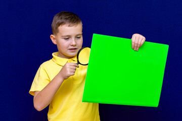 Close up portrait of Caucasian school boy student looking at paper using magnifying glass. education concept