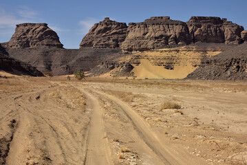 SAHARA DESERT IN ALGERIA. SAFARI AND ADVENTURE IN TADRART NATIONAL PARK. SAND DUNES AND BLACK MOUNTAINS