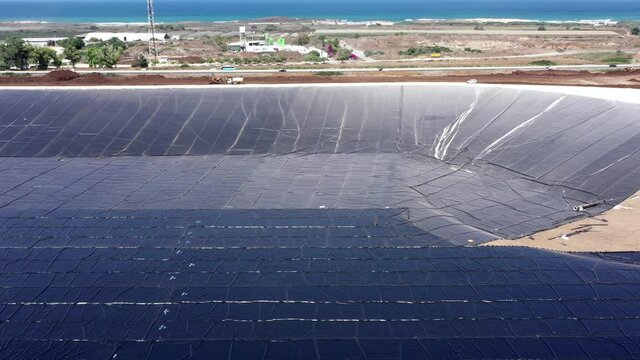 Water reservoir construction site with newly installed plastic lining sheets, Aerial view.