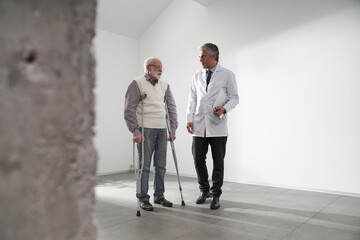 Aged man using crutches visits his general practitioner