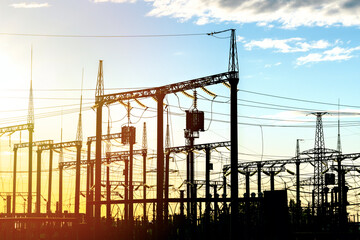 Distribution electric substation with high-voltage power lines and transformers at sunset, electric...