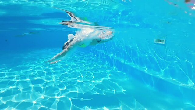 Underwater shooting. Girl dive in blue swimming pool.