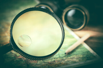 Magnifying glass and binoculars on the old map.