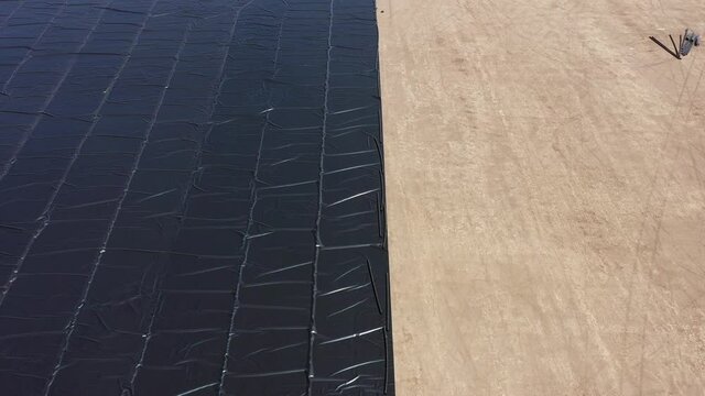 Water reservoir construction site with newly installed plastic lining sheets, Aerial view.