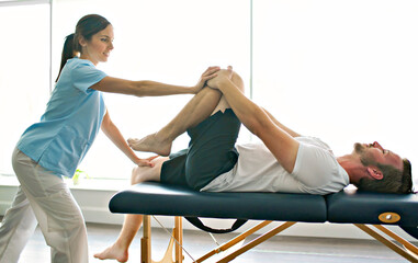 physiotherapist doing treatment with patient in bright office with leg training